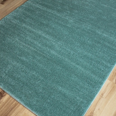 Tapete felpudo verde sobre piso de madeira clara