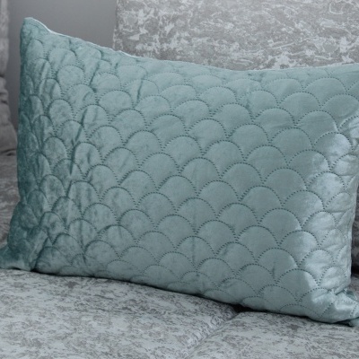 Almofada azul claro com padrão de ondas sobre sofá cinza aveludado
