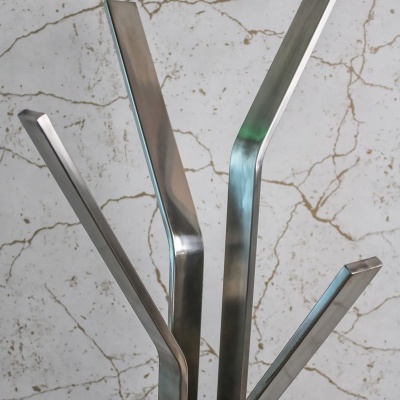 Cabide de pé metálico prateado com quatro ganchos, fundo branco com veios cinzentos