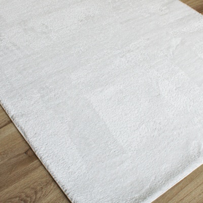 Tapete felpudo branco sobre chão de madeira clara