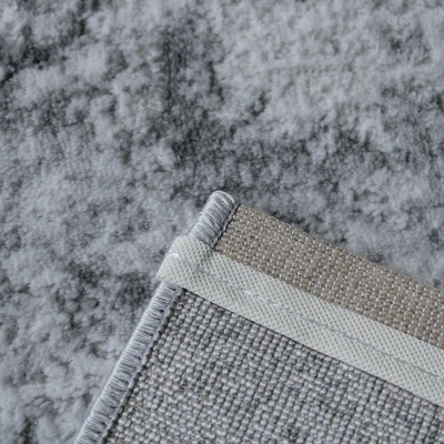 Tapete cinzento com padrão abstrato e bordas costuradas em vista detalhada