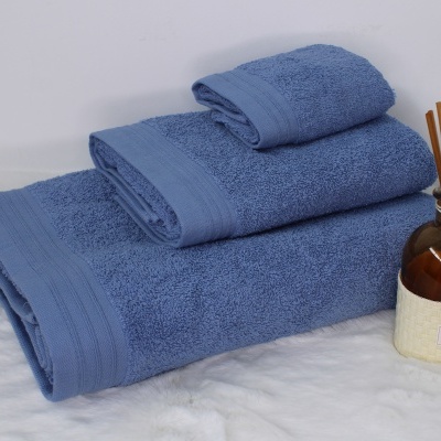 Conjunto de toalhas azuis empilhadas com frasco de aroma ao lado