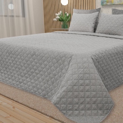 Colcha cinzenta matelassada com padrão de losangos numa cama