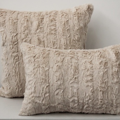 Duas almofadas peludas bege claro sobre superfície branca