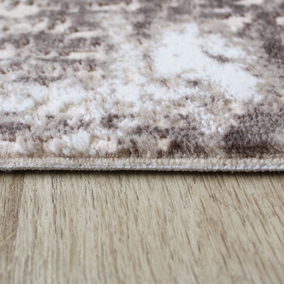 Tapete felpudo com padrão abstrato em tons naturais sobre chão de madeira clara