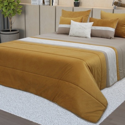 Cama com colcha acolchoada mostarda, bege e branca com almofadas correspondentes