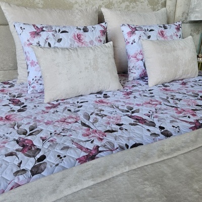 Roupa de cama com padrão floral rosa e almofadas beges