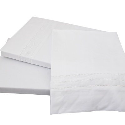 Jogo de roupa de cama branco com bordado e tecido liso sobre superfície branca