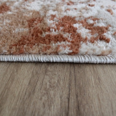 Tapete felpudo bege e castanho sobre chão de madeira clara