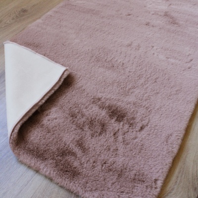 Tapete rosa claro com verso branco em chão de madeira clara