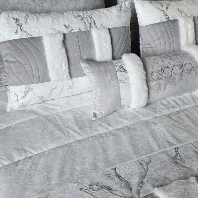 Conjunto de almofadas decorativas cinza e branco com várias texturas em cama.