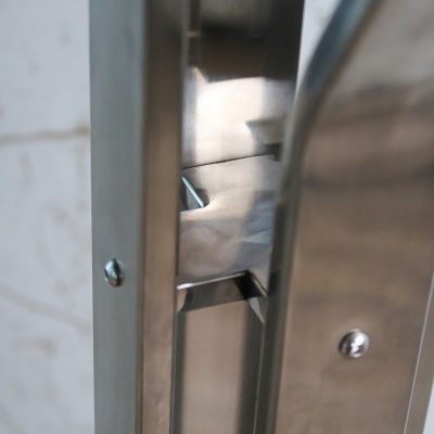 Fechadura metálica prateada embutida numa porta metálica com parafusos visíveis