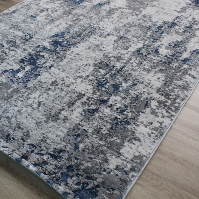 Tapete abstrato cinza, branco e azul sobre chão de madeira clara