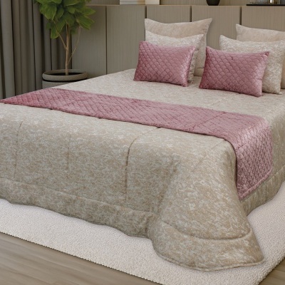 Cama com colcha bege e detalhes rosa em ambiente interior com cortinas e planta
