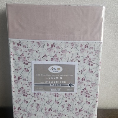 Jogo de cama rosa claro com padrão floral rosa escuro, embalado em plástico