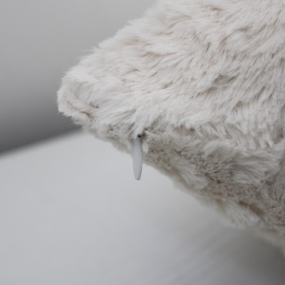 Almofada de pelo sintético branco-creme com etiqueta