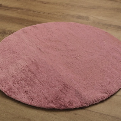 Tapete redondo cor de rosa em chão de madeira
