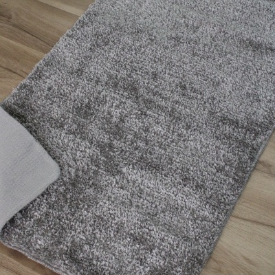 Tapete felpudo cinzento sobre chão de madeira