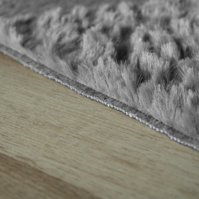 Tapete cinza felpudo sobre piso de madeira clara