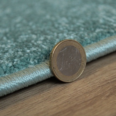 Tapete azul claro com textura felpuda e moeda de 1 euro encostada para comparação.