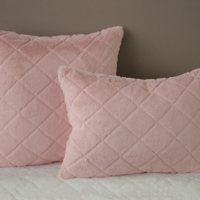 Duas almofadas rosa claro acolchoadas em losango numa cama