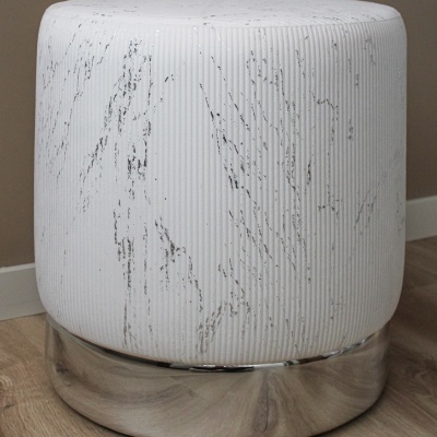 Pufe redondo branco com padrão marmoreado e base cromada sobre chão de madeira clara