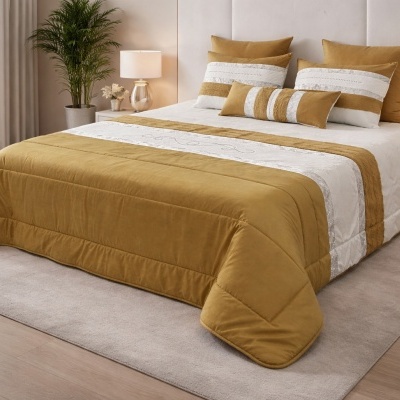 Conjunto de cama castanho mostarda e branco com almofadas e edredão bordado sobre cama com cabeceira creme