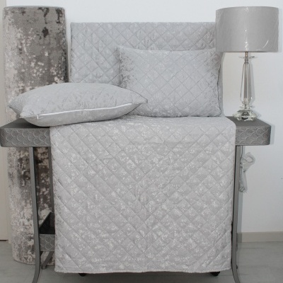 almofadas e manta cinza acolchoada com mesa e candeeiro cinza