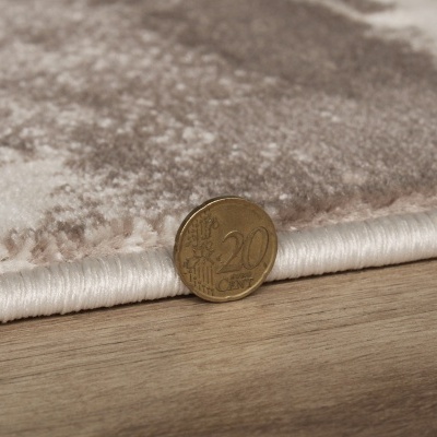 Tecido bege com padrão castanho junto a moeda de 20 centavos de euro sobre madeira