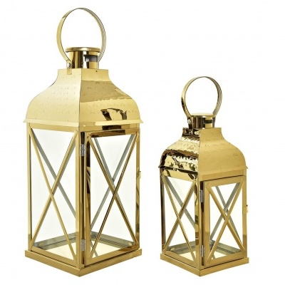 Duas lanternas douradas de metal com vidro colocadas lado a lado