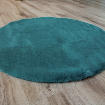 Tapete redondo verde-azulado sobre pavimento de madeira clara