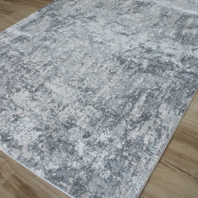 Tapete cinza e branco com padrão abstrato sobre chão de madeira