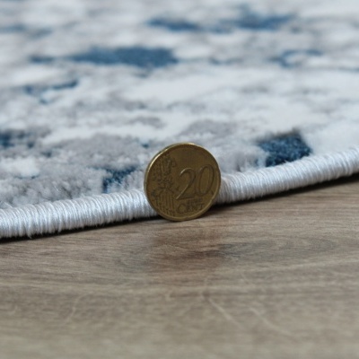 Tapete cinza, azul e branco com bordas brancas e moeda de 20 cêntimos sobre pavimento madeira