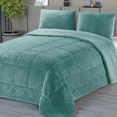 Cama com edredão e almofadas verde-água em tecido felpudo com padrão geométrico