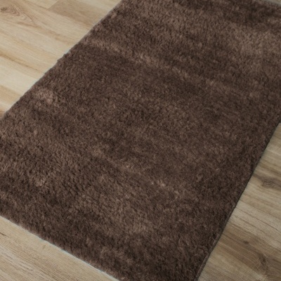 Tapete felpudo castanho escuro sobre chão de madeira