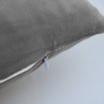 Almofada cinzenta com fecho de correr branco visível na lateral