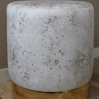 Pufe redondo branco com base dourada sobre chão de madeira