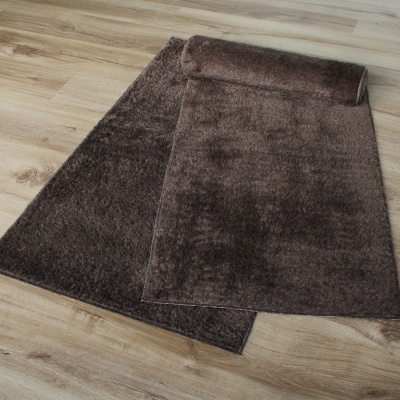 tapete castanho felpudo sobre chão madeira