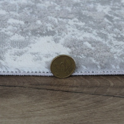 tecido branco e cinzento com padrão floral em relevo e moeda de 20 centavos