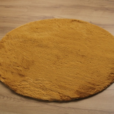 Tapete redondo amarelo mostarda felpudo sobre chão de madeira clara