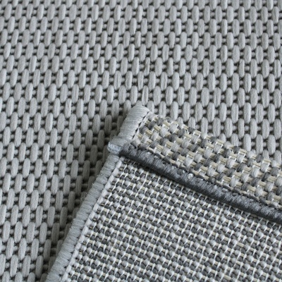 Tapete cinza trançado com borda cinza e dobra mostrando o verso