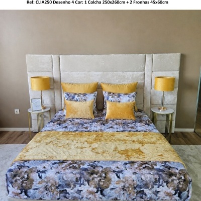 Cama com colcha floral azul e amarelo, almofadas amarelas e cabeceira estofada bege