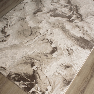 Tapete retangular com padrão abstrato em tons de bege e castanho sobre chão de madeira clara