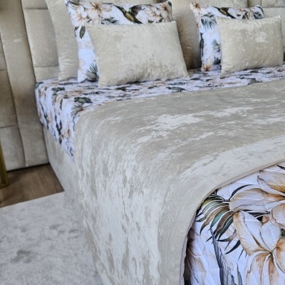 Cama com cabeceira e roupa de cama bege aveludada e floral
