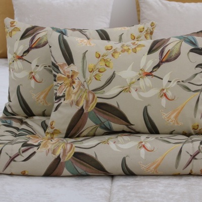 Almofadas e manta com padrão floral sobre sofá cinza claro