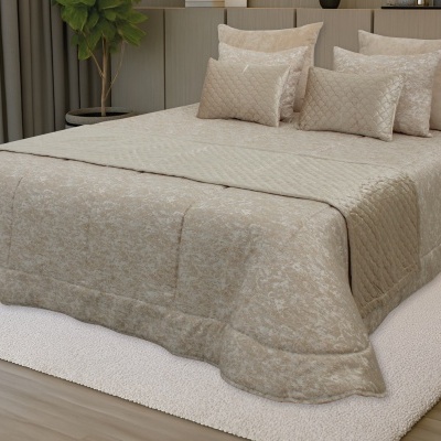 Edredão bege matelassê com almofadas decorativas em quarto com tapete branco