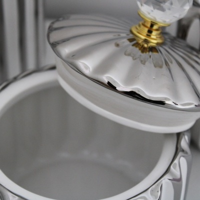 Pote de porcelana branca com tampa metálica prateada e punho em vidro