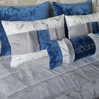 Almofadas decorativas azuis, cinzentas e brancas sobre cama cinza