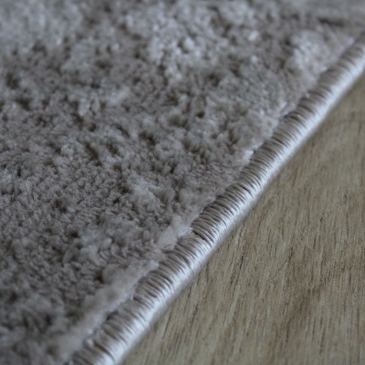 Tapete cinza claro com borda costurada em chão de madeira