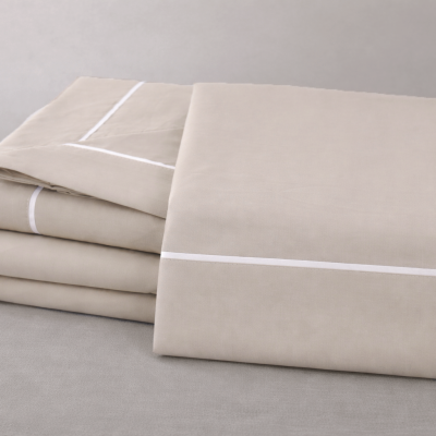 Jogo de cama bege com linhas brancas sobre superfície cinza